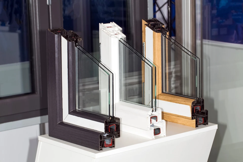 Intérieur d'un showroom de menuiserie avec échantillons de profilés de fenêtres disposés sur étagère blanche