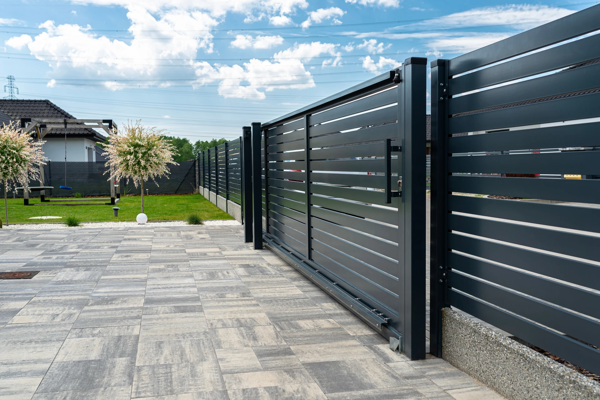Portail coulissant moderne en aluminium gris anthracite avec lames horizontales ajourées, monté sur rail au sol